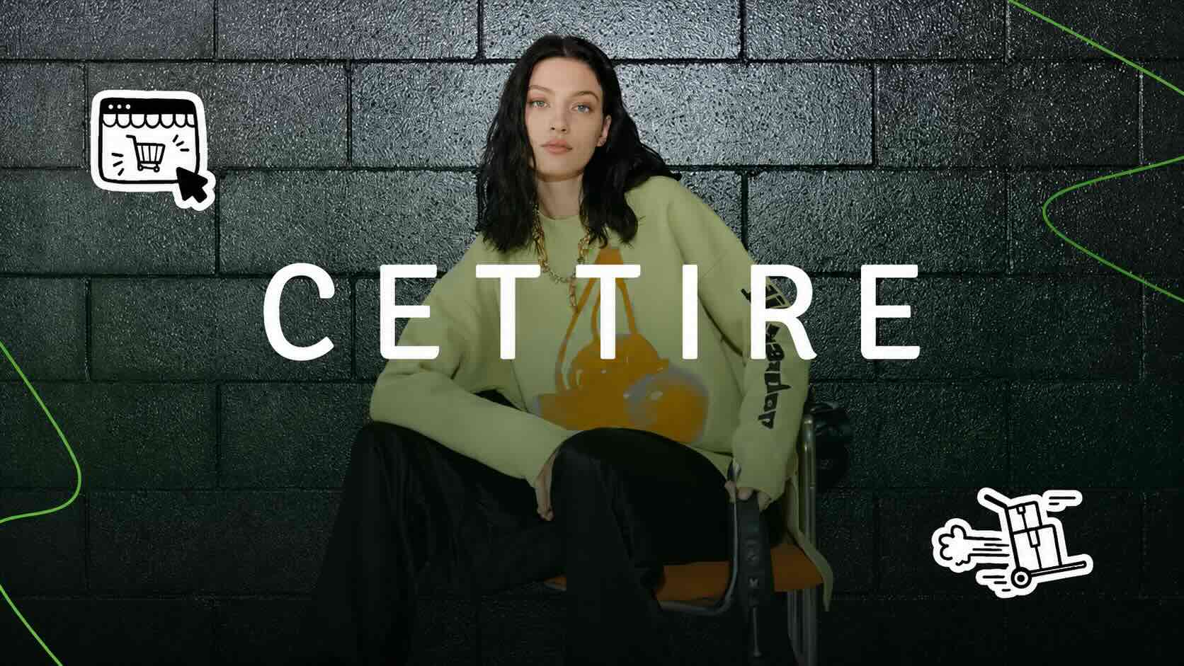 Cettire brand campaign image — model in an oversized designer sweatshirt against a dark brick wall